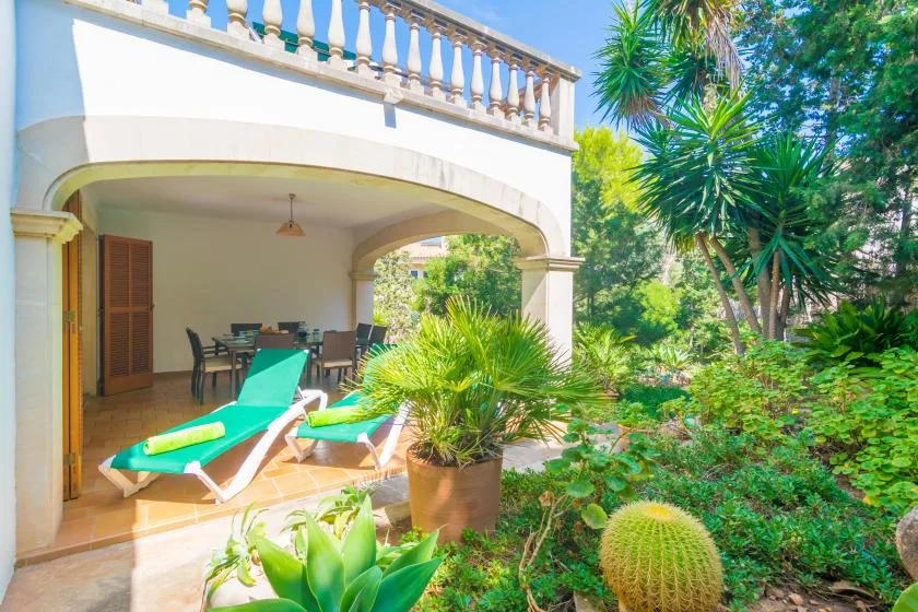 Un patio sombreado con asientos de descanso se abre a un jardín frondoso.