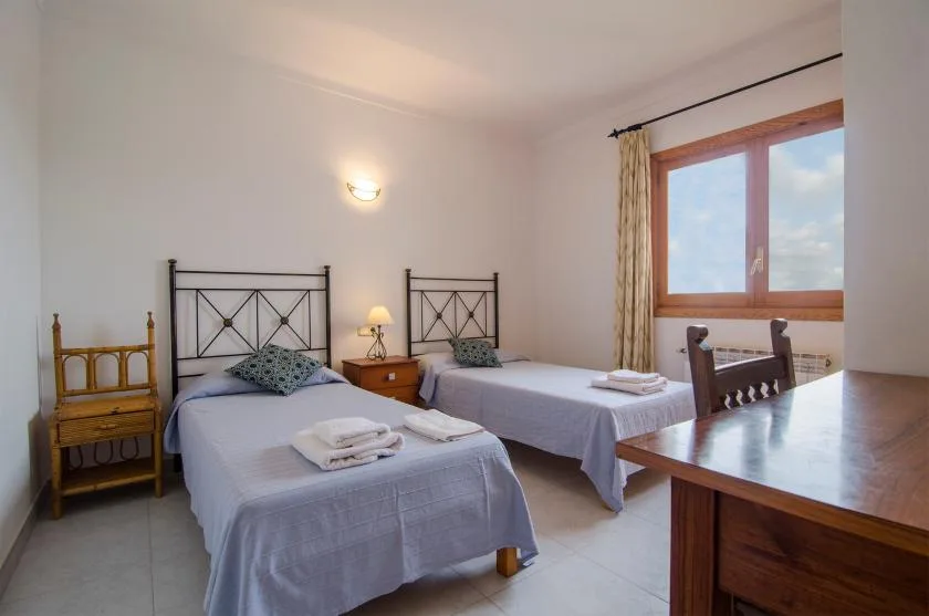 A bright bedroom with two single beds and a large window.