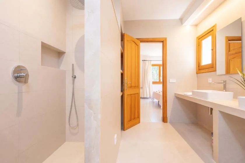 A bright bathroom with a shower and a long vanity beside the doorway.