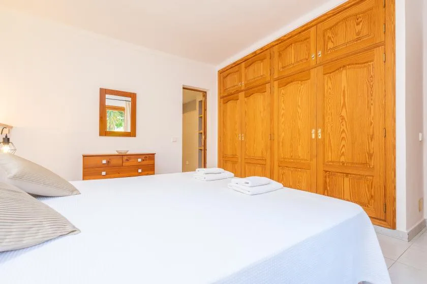 A bedroom with a large bed and wooden built-in wardrobes.