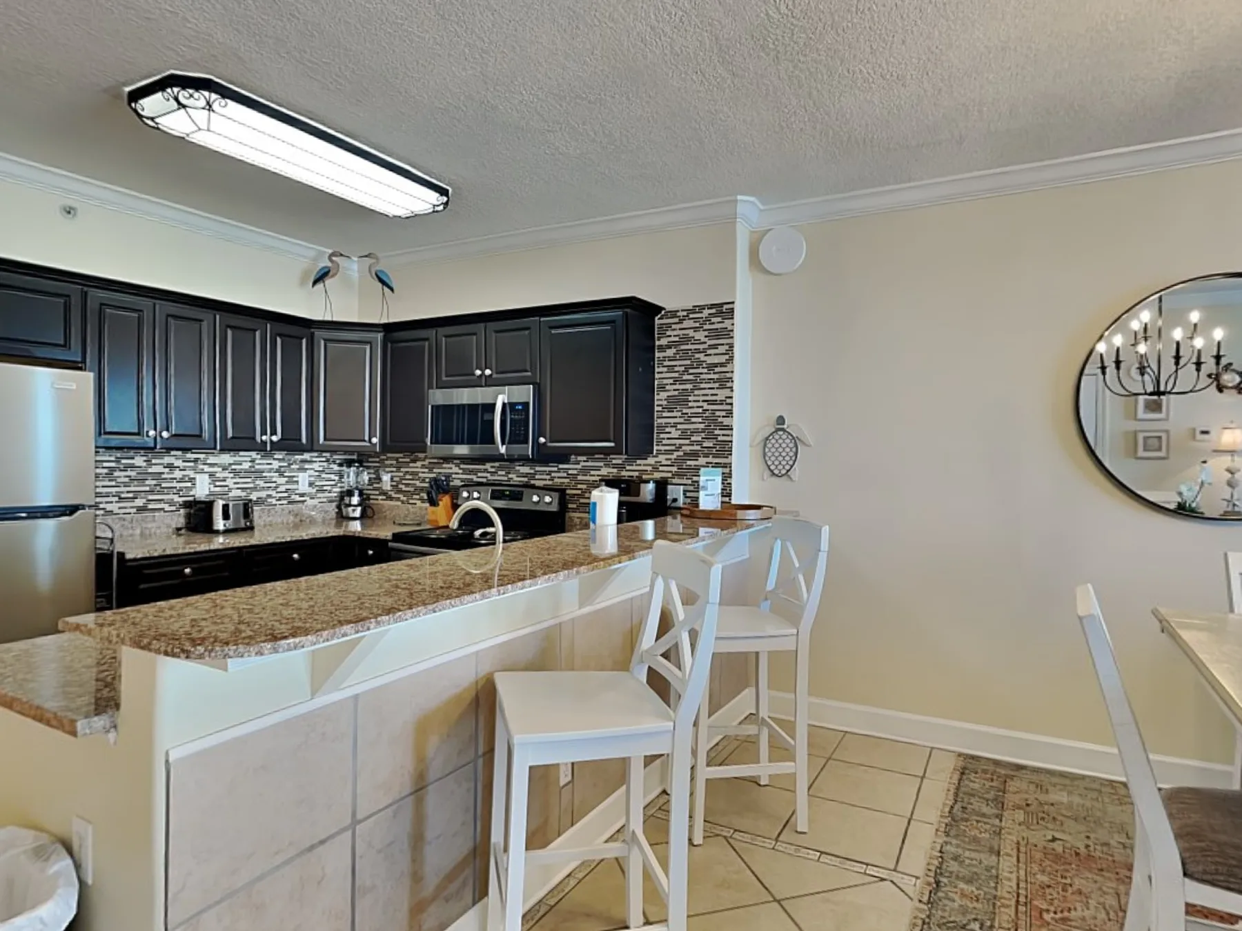 A kitchen with dark cabinets, a counter, and bar seating.
