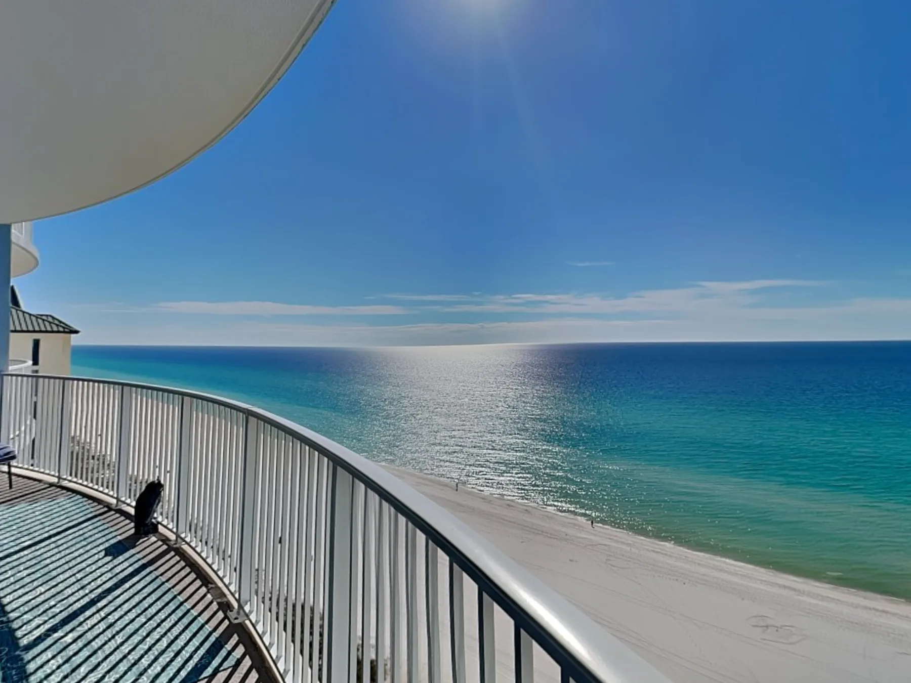 A curved balcony overlooks a sandy beach and the sea.
