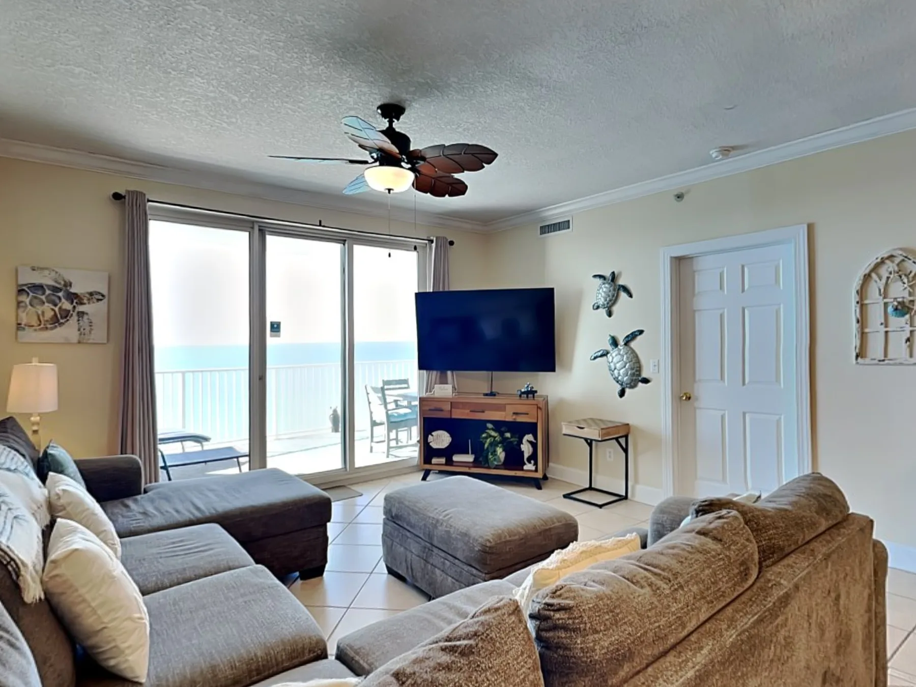 A living room with sectional seating, a television, and sliding glass doors.