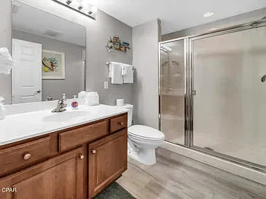 Un baño con un mueble de madera, lavabo y ducha de vidrio.