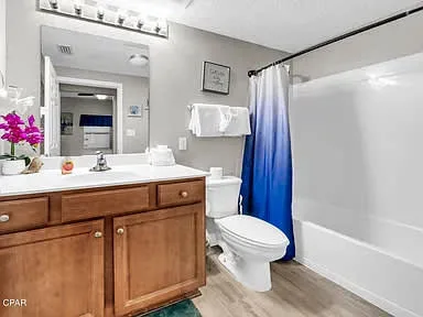 Un baño con un mueble de madera, un espejo y una cortina de ducha azul.