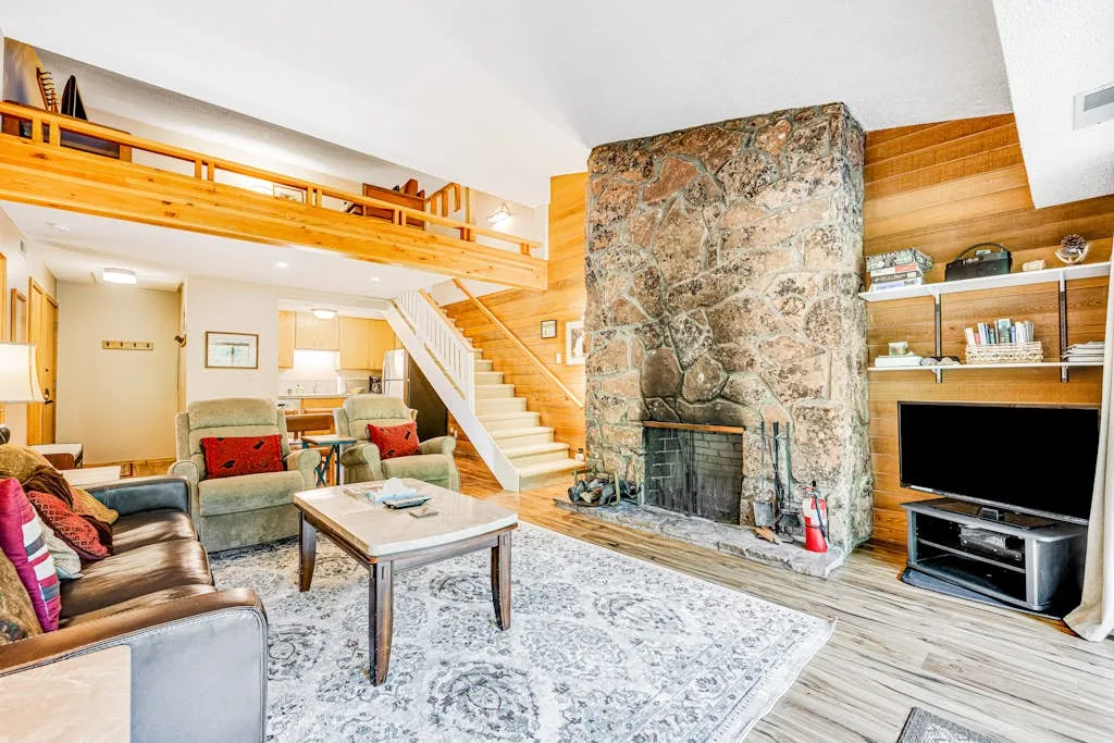 A living room with seating, a coffee table, and a large stone fireplace.