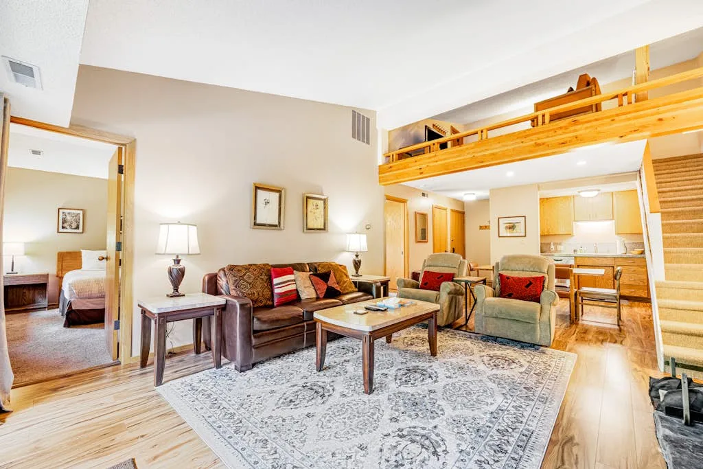 A living room with seating and a coffee table beneath a wooden loft.