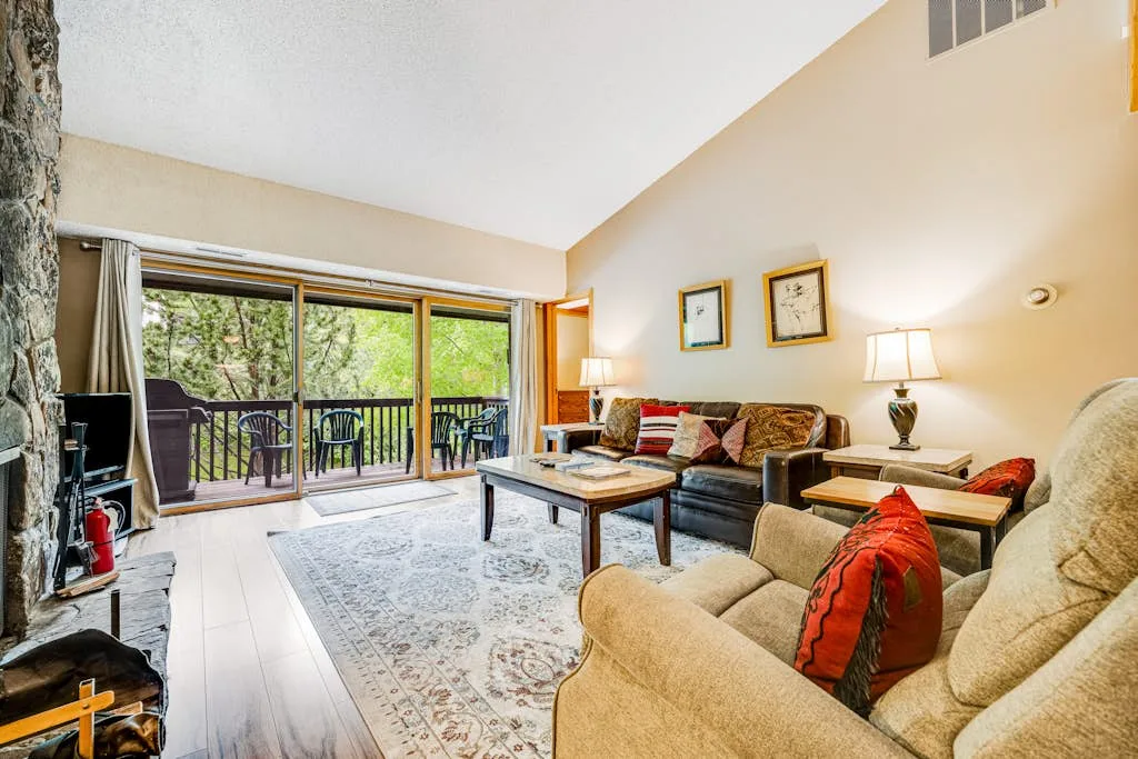 A living room with seating, a coffee table, and glass doors opening to a balcony.
