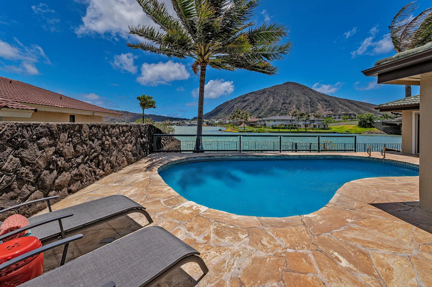 Una piscina tiene vistas a un lago y una montaña, con asientos reclinables cerca.