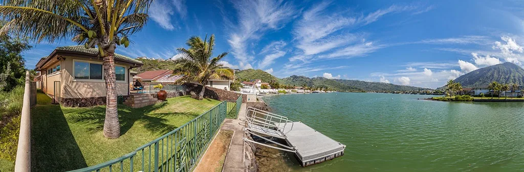 Una casa junto al lago, con un jardín de césped y un pequeño muelle.