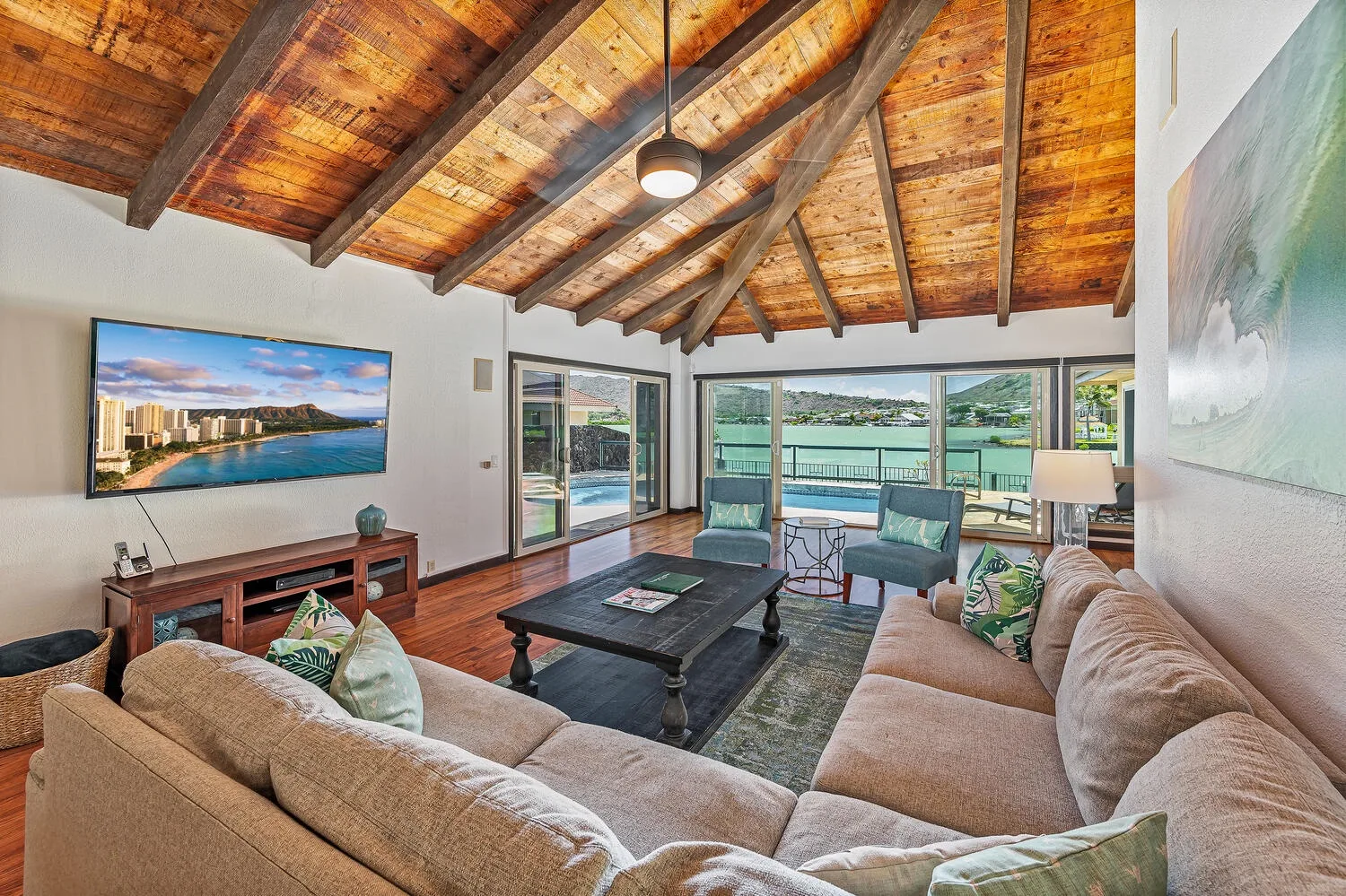 Una sala de estar con asientos, una mesa de centro y grandes ventanas con vista al agua.