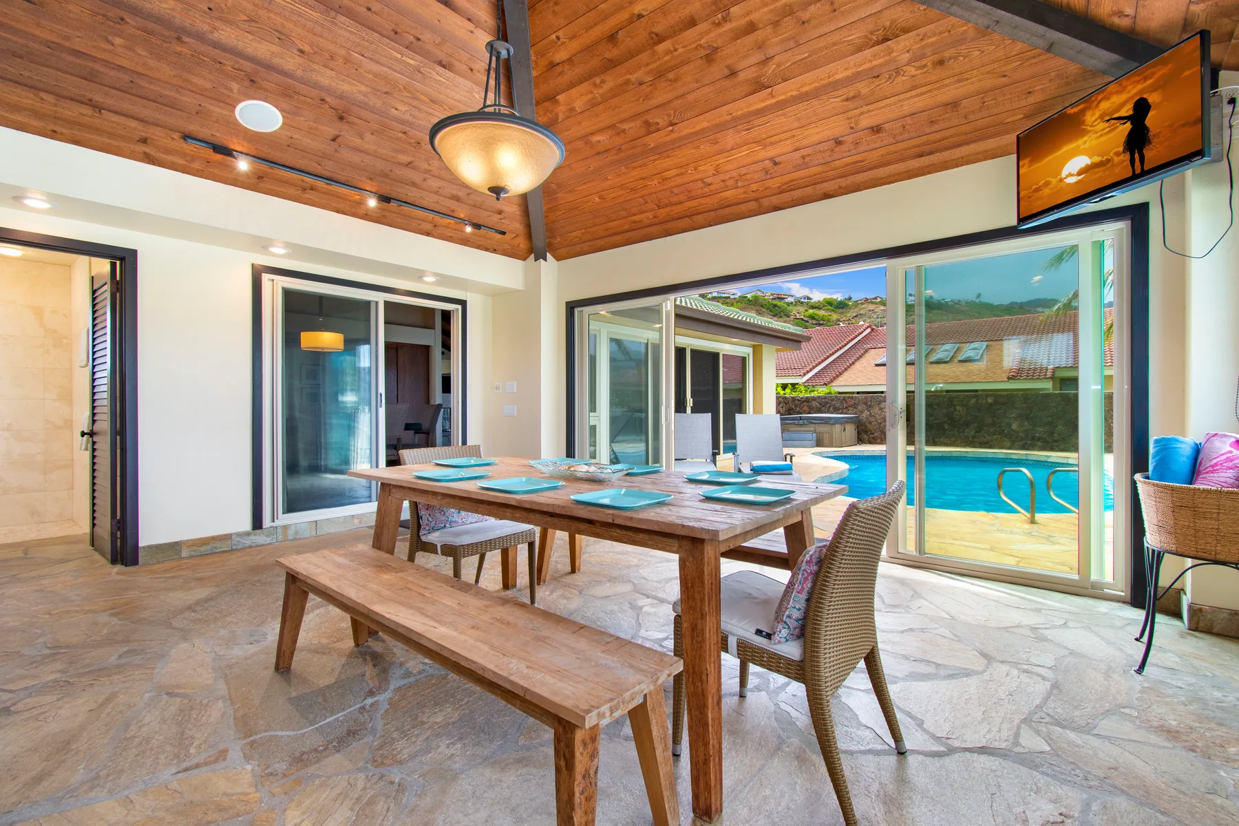 Comedor con una mesa de madera y puertas corredizas de vidrio con vista a una piscina.