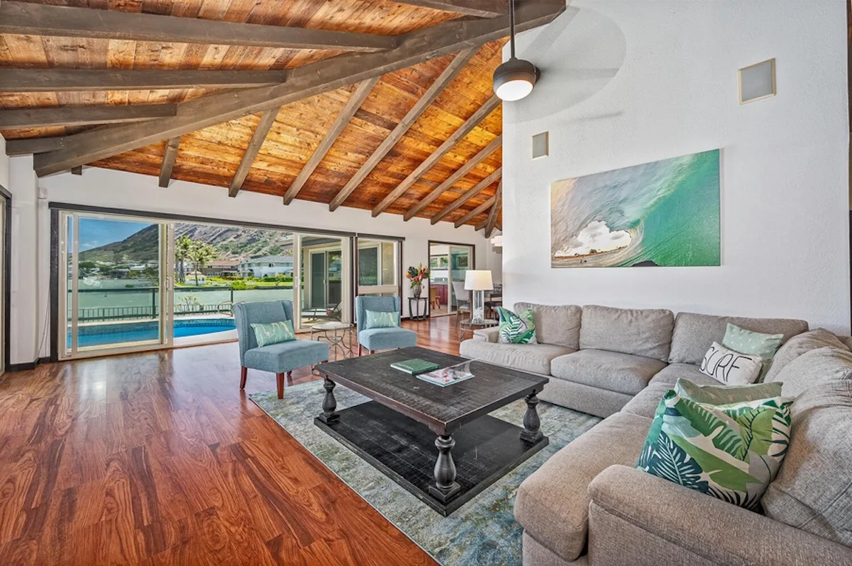 Una sala de estar con asientos seccionales y grandes ventanas con vista a una piscina.