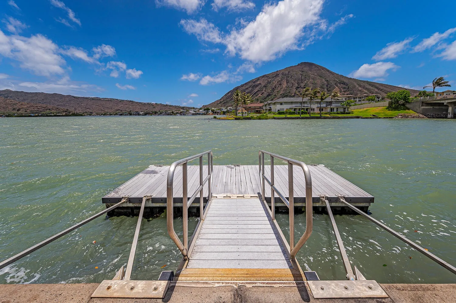 Un muelle de madera se adentra en un lago, con una montaña al otro lado del agua.
