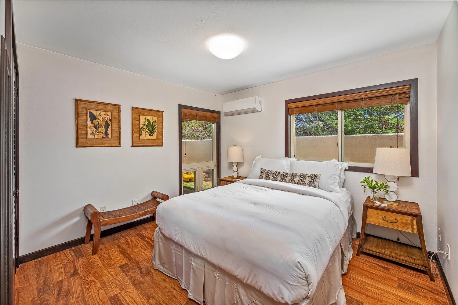 Un dormitorio con una cama bien tendida, cuadros enmarcados y una ventana.
