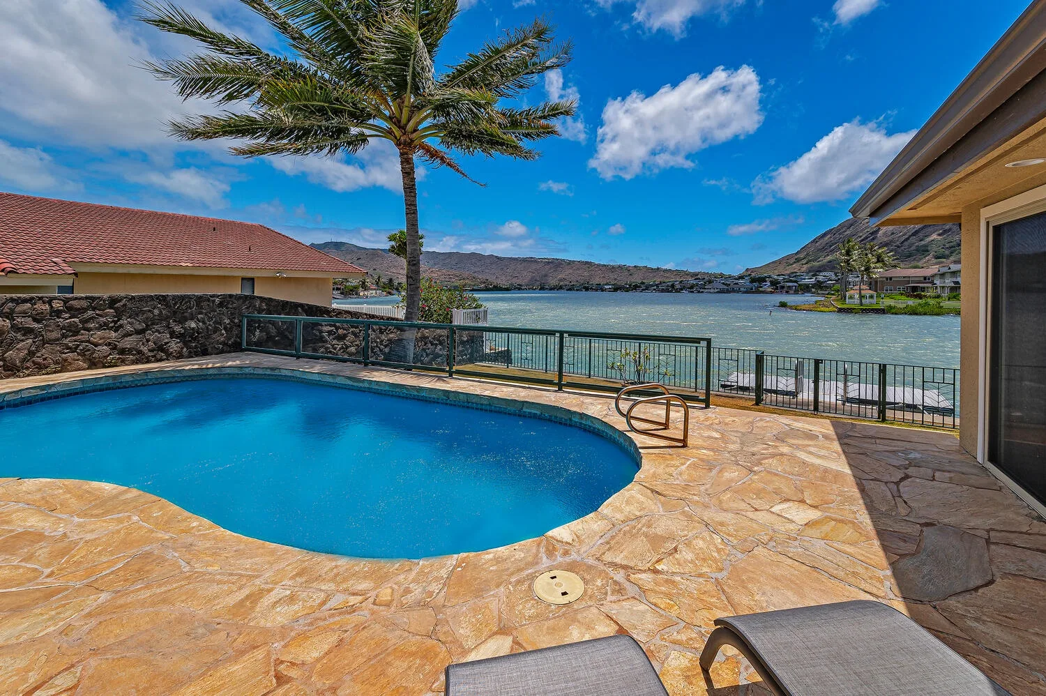 Una piscina al aire libre y un patio de piedra dan a un lago.
