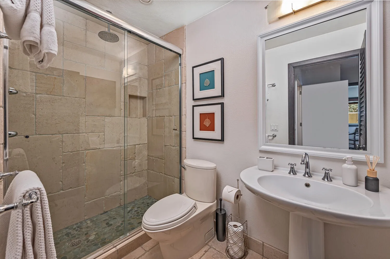 Un baño con ducha de vidrio, inodoro y lavabo.
