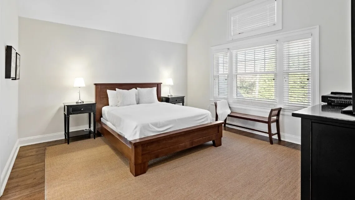Un dormitorio luminoso con una cama de madera y una gran ventana con persianas.