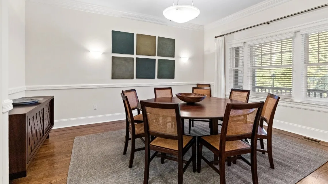 Comedor con una mesa de madera y sillas bajo una lámpara colgante.