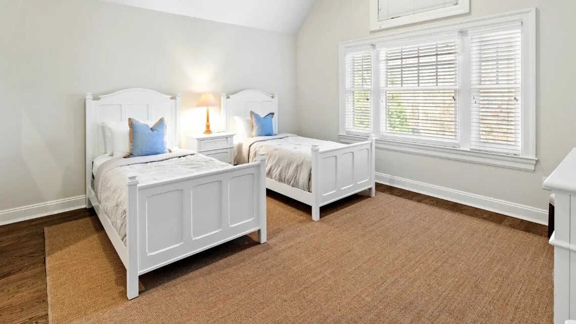 Un dormitorio luminoso con dos camas individuales y una ventana grande.