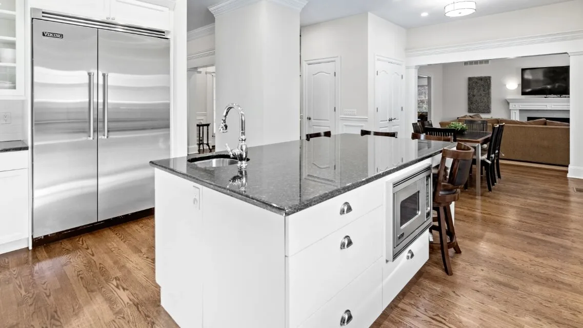 Una cocina luminosa con una isla central y un refrigerador de acero inoxidable.