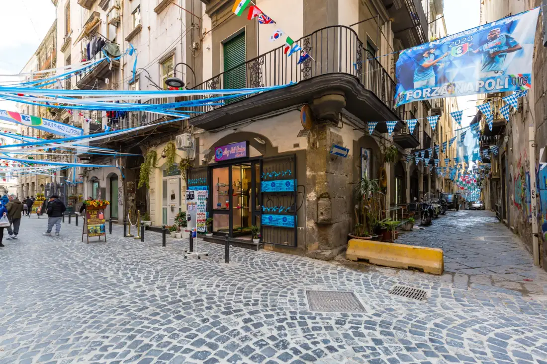 Una calle empedrada flanqueada por edificios y coloridas banderas en lo alto.