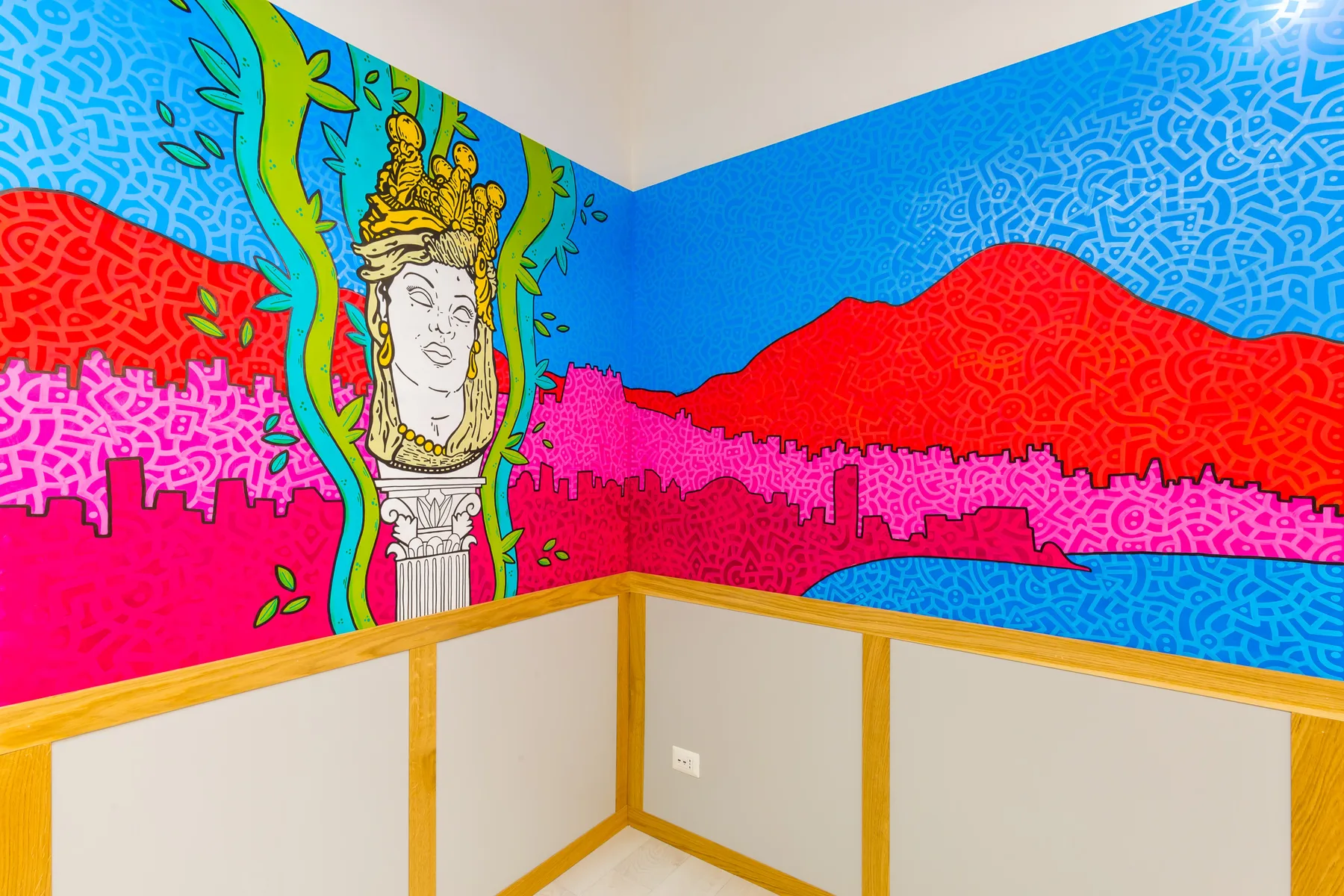 Una esquina de una habitación presenta murales coloridos con un retrato y un paisaje.