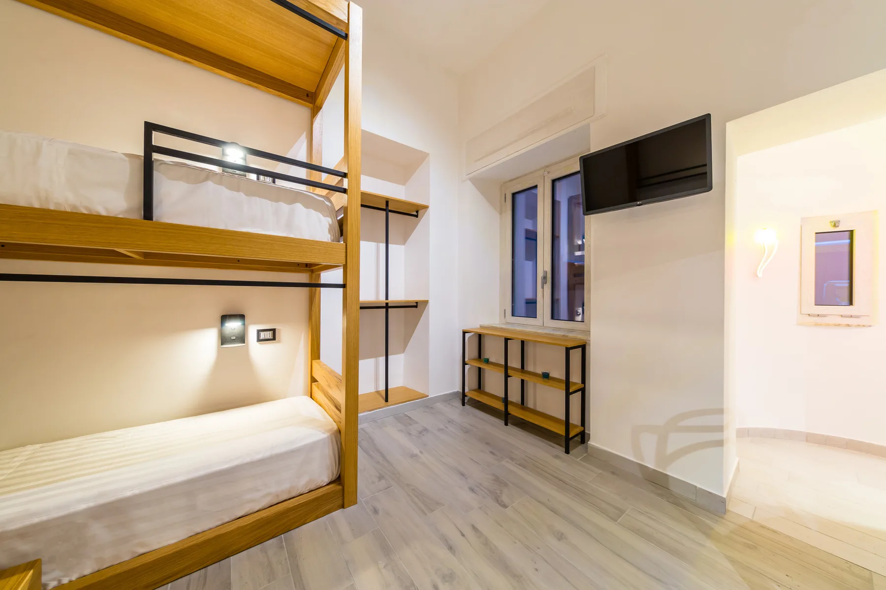 Zona para dormir con literas, una ventana y un televisor en la pared.