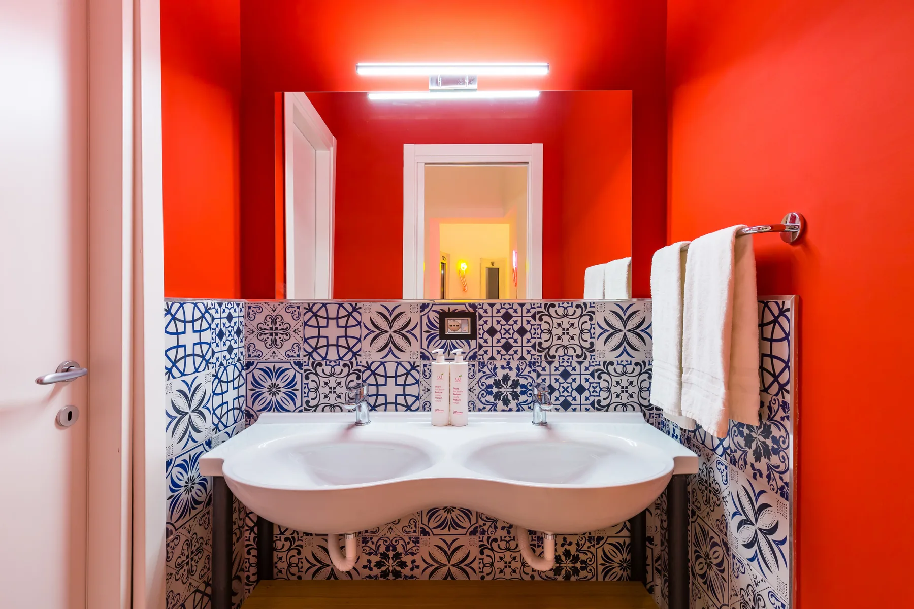 Un baño luminoso con un lavabo doble debajo de un espejo grande.