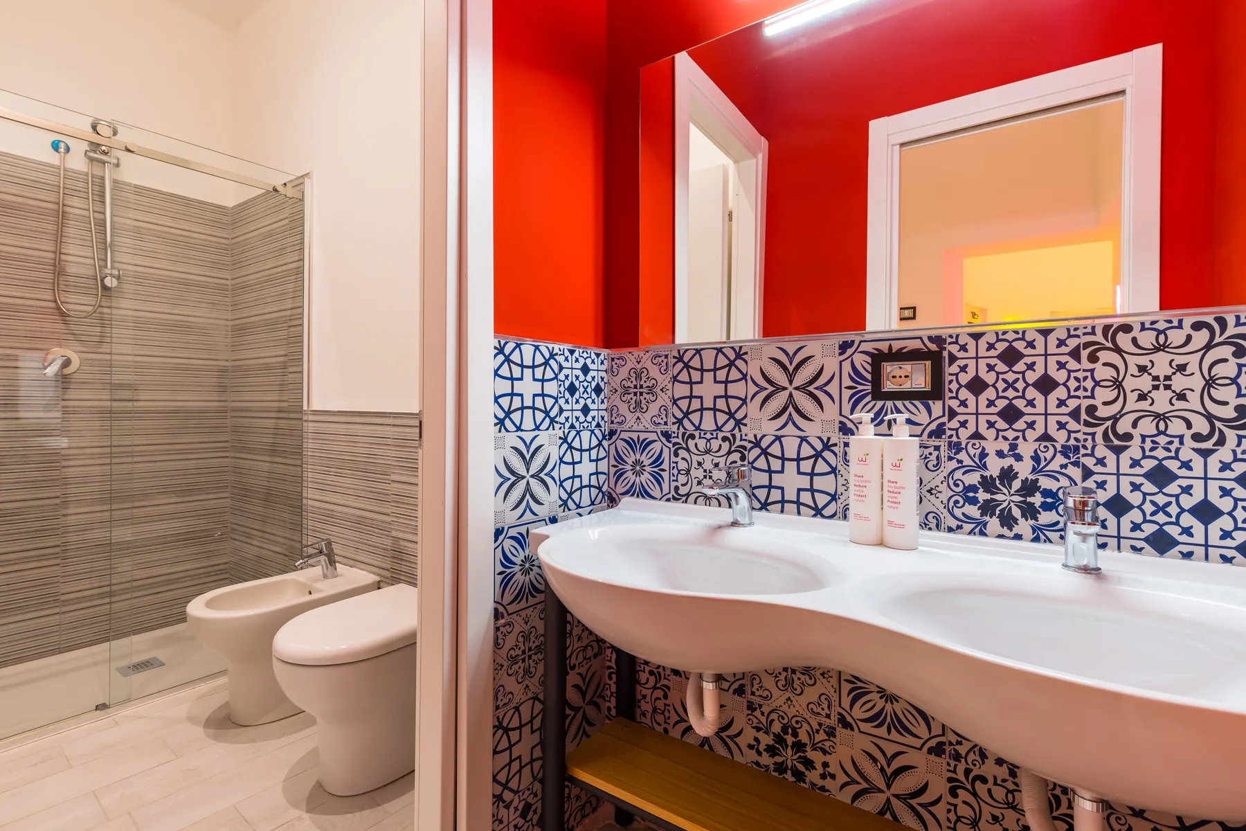 Un baño con un lavabo de azulejos estampados junto a una ducha y un inodoro.