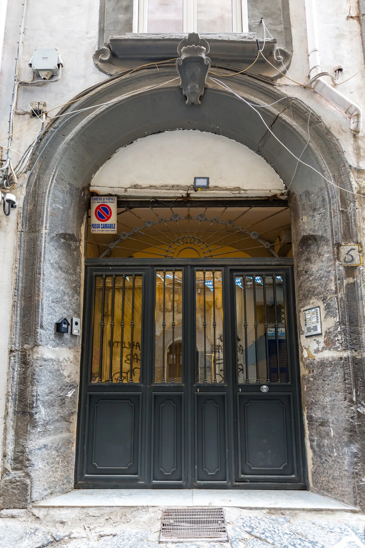 Una entrada de edificio con arco ornamentado y puertas oscuras con paneles de vidrio.