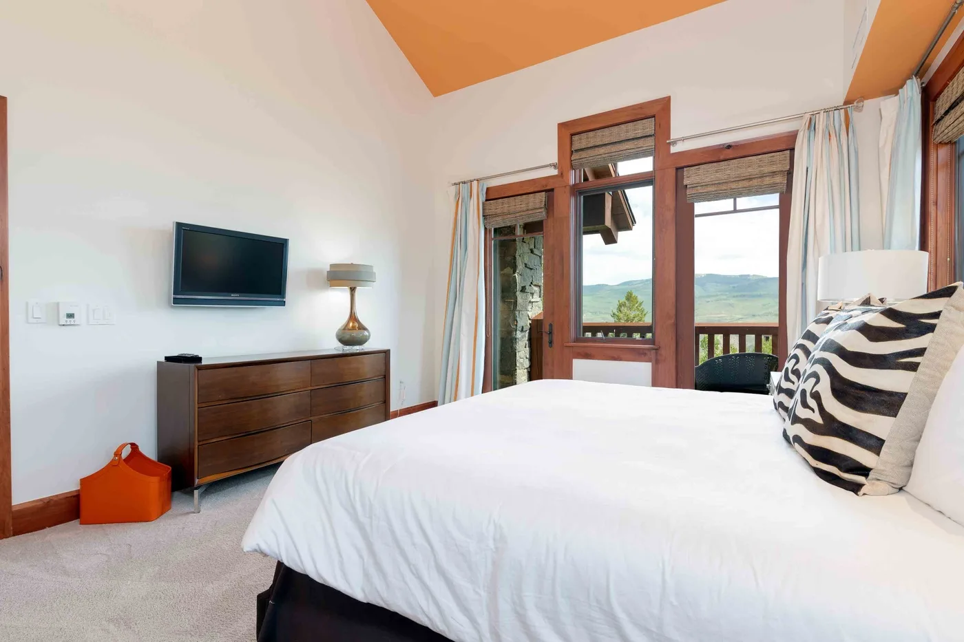 Un dormitorio con una cama grande, una cómoda y ventanas con vistas a colinas verdes.