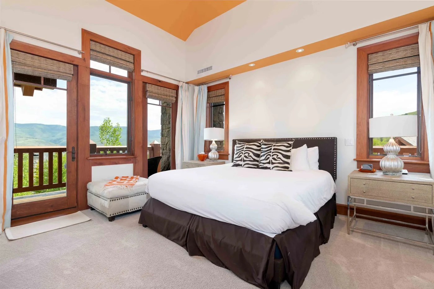 Un dormitorio con una cama junto a ventanas altas con vistas a un balcón.