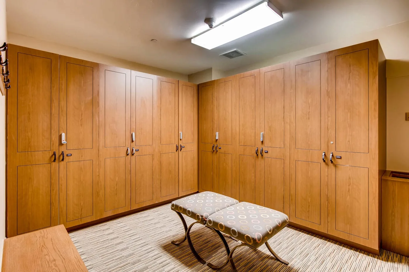 Una sala con taquillas de madera y un banco acolchado en primer plano.