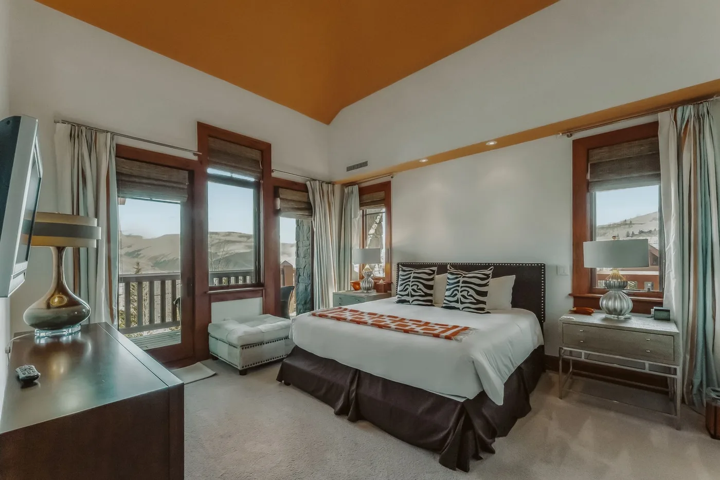 Un dormitorio con una cama, ventanas y cortinas.