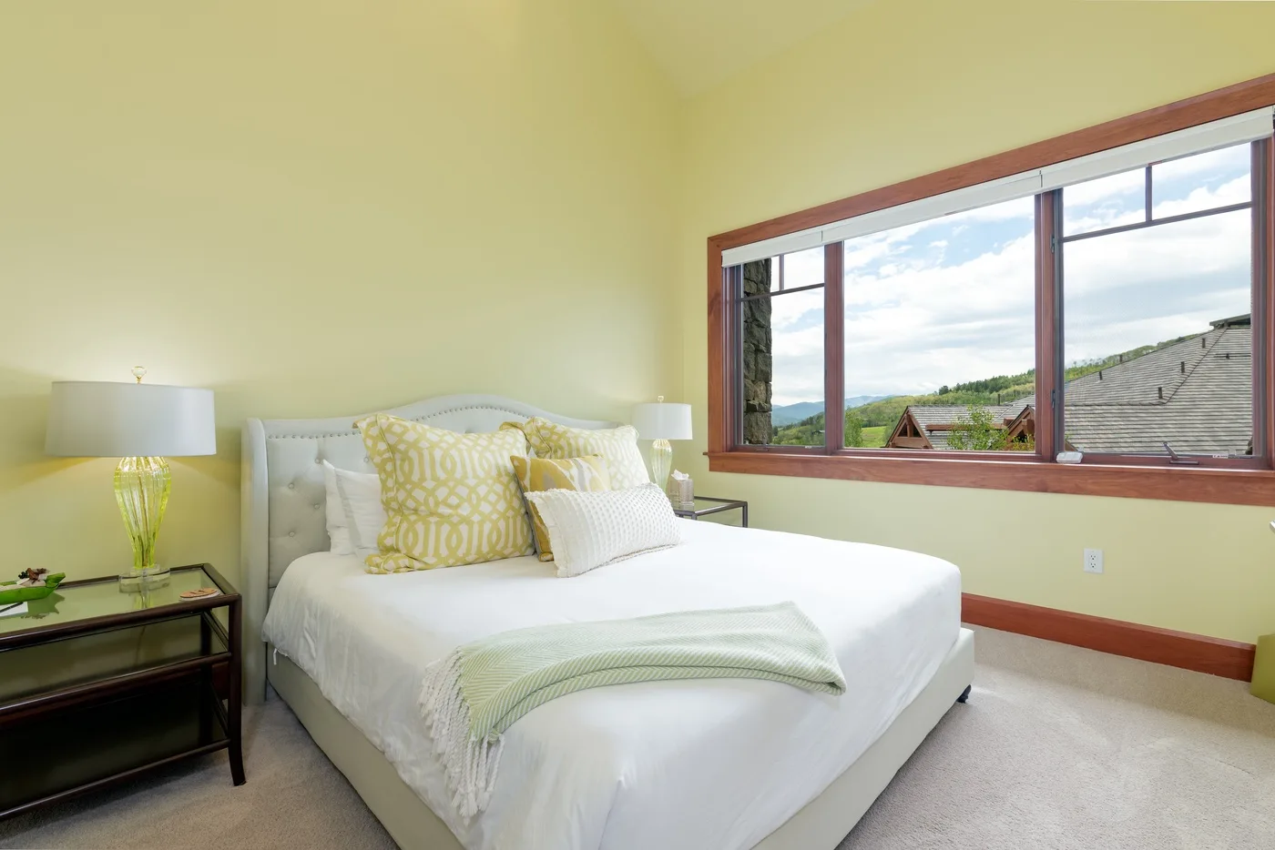 Un dormitorio luminoso con una cama blanca junto a una ventana grande.