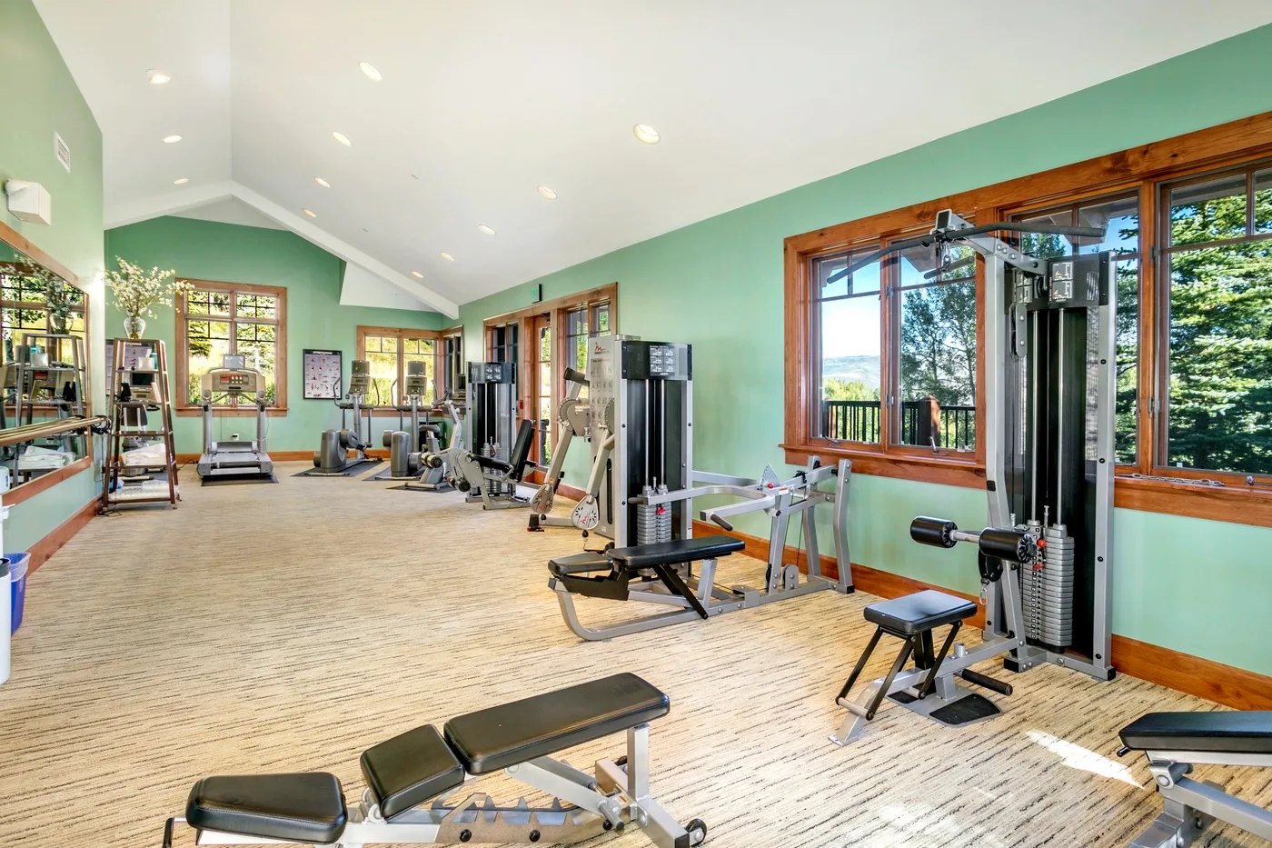 Una amplia sala de ejercicios con máquinas de entrenamiento y grandes ventanas.