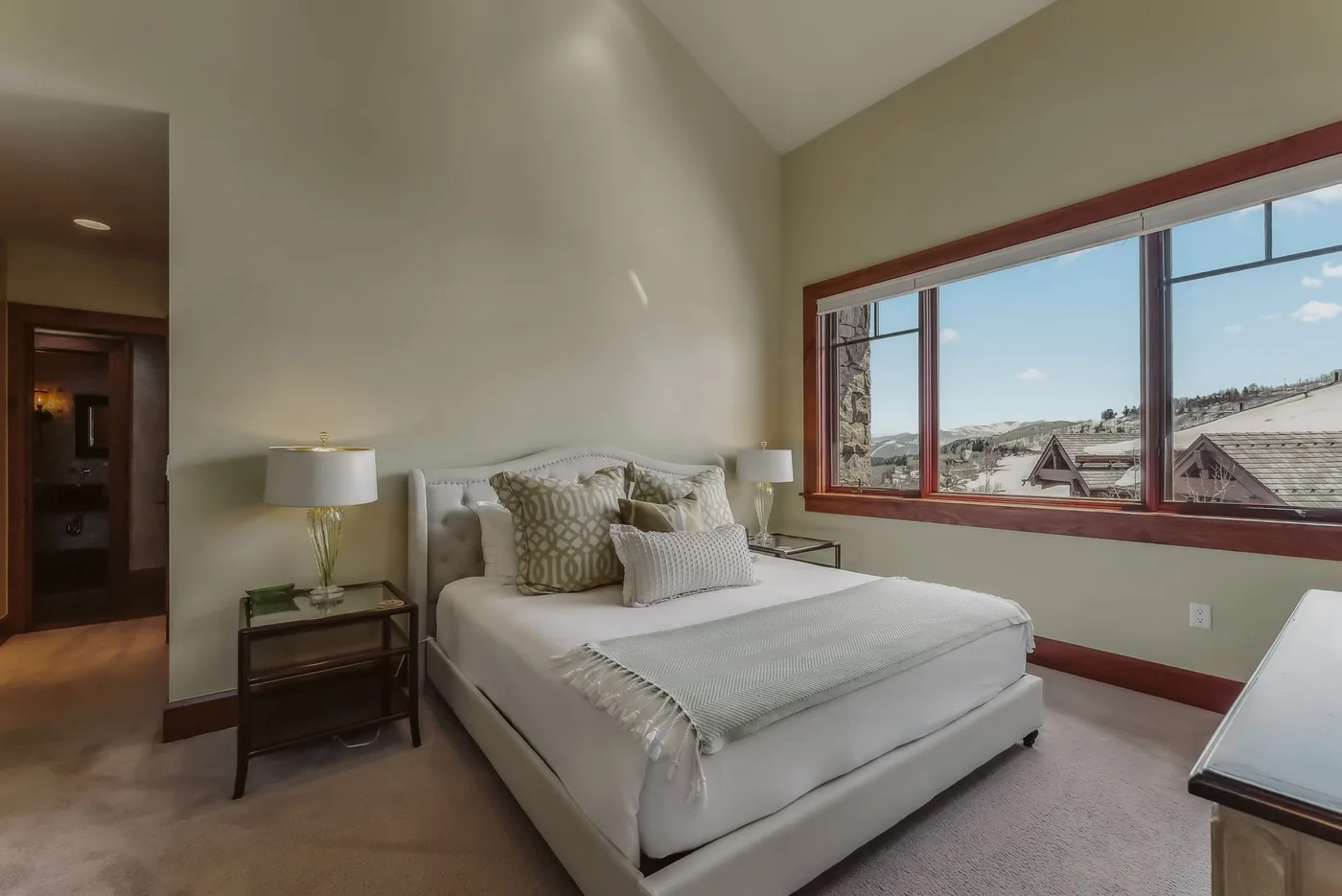 Un dormitorio luminoso con una cama grande junto a una ventana amplia.