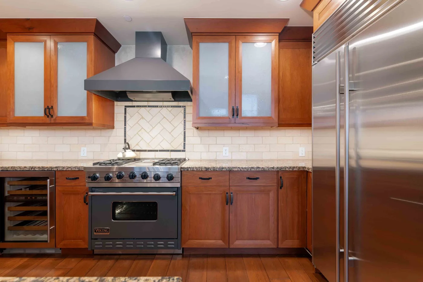 Una cocina con gabinetes de madera, una estufa y un refrigerador de acero inoxidable.