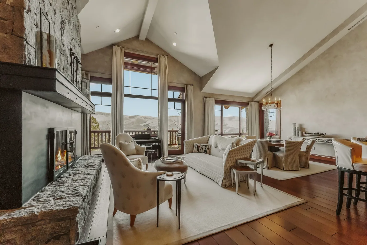 Una amplia sala de estar con chimenea, asientos y grandes ventanas.