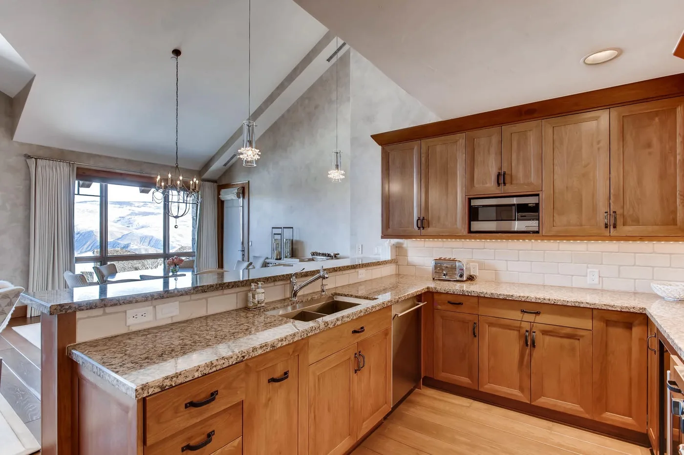 Una cocina con gabinetes de madera y una encimera de piedra junto a un comedor.