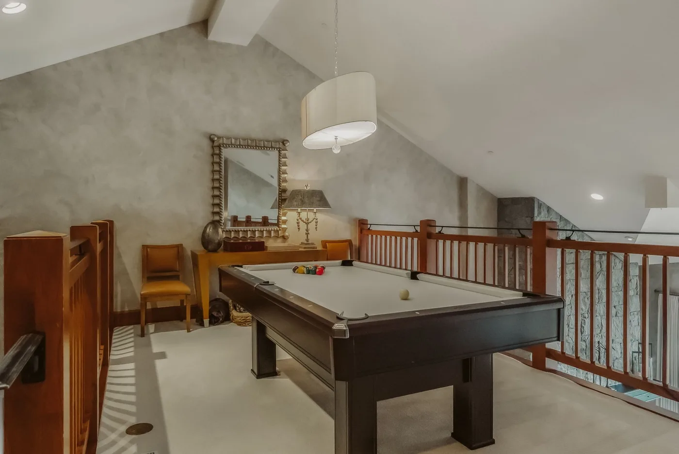 Una sala de billar con una mesa de pool bajo un techo inclinado.