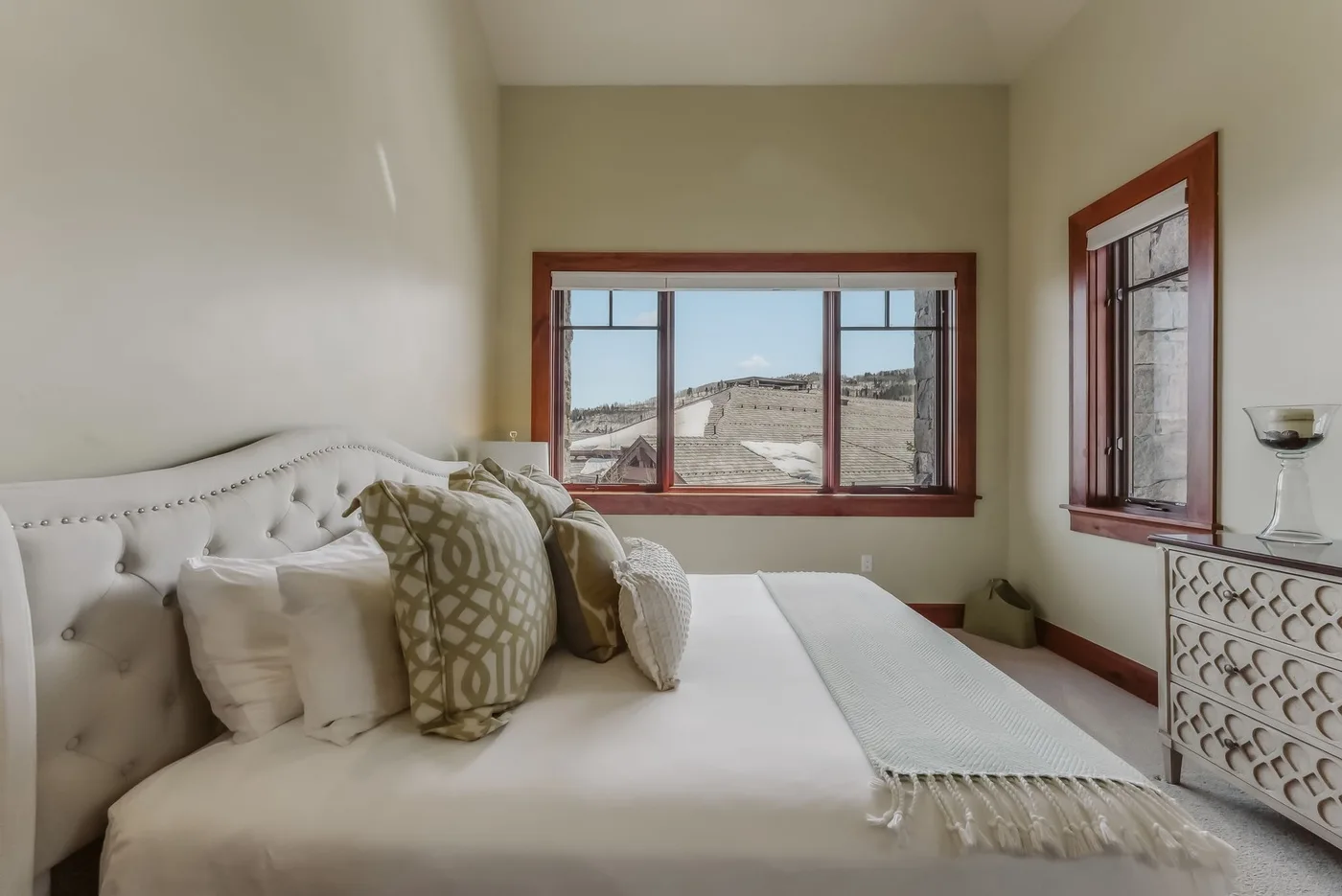 Un dormitorio con una cama y ventanas con vistas a un paisaje árido.