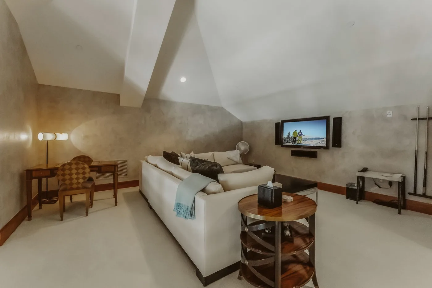 Una sala de estar con asientos alrededor de una mesa baja de madera y un televisor en la pared.