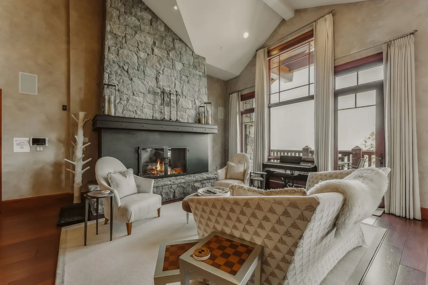 A bright living room with seating arranged around a stone fireplace.