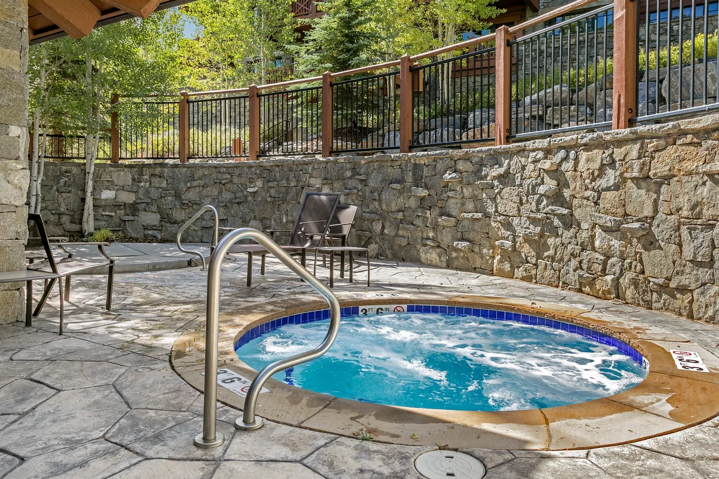 A small outdoor pool sits beside a stone wall and patio seating.