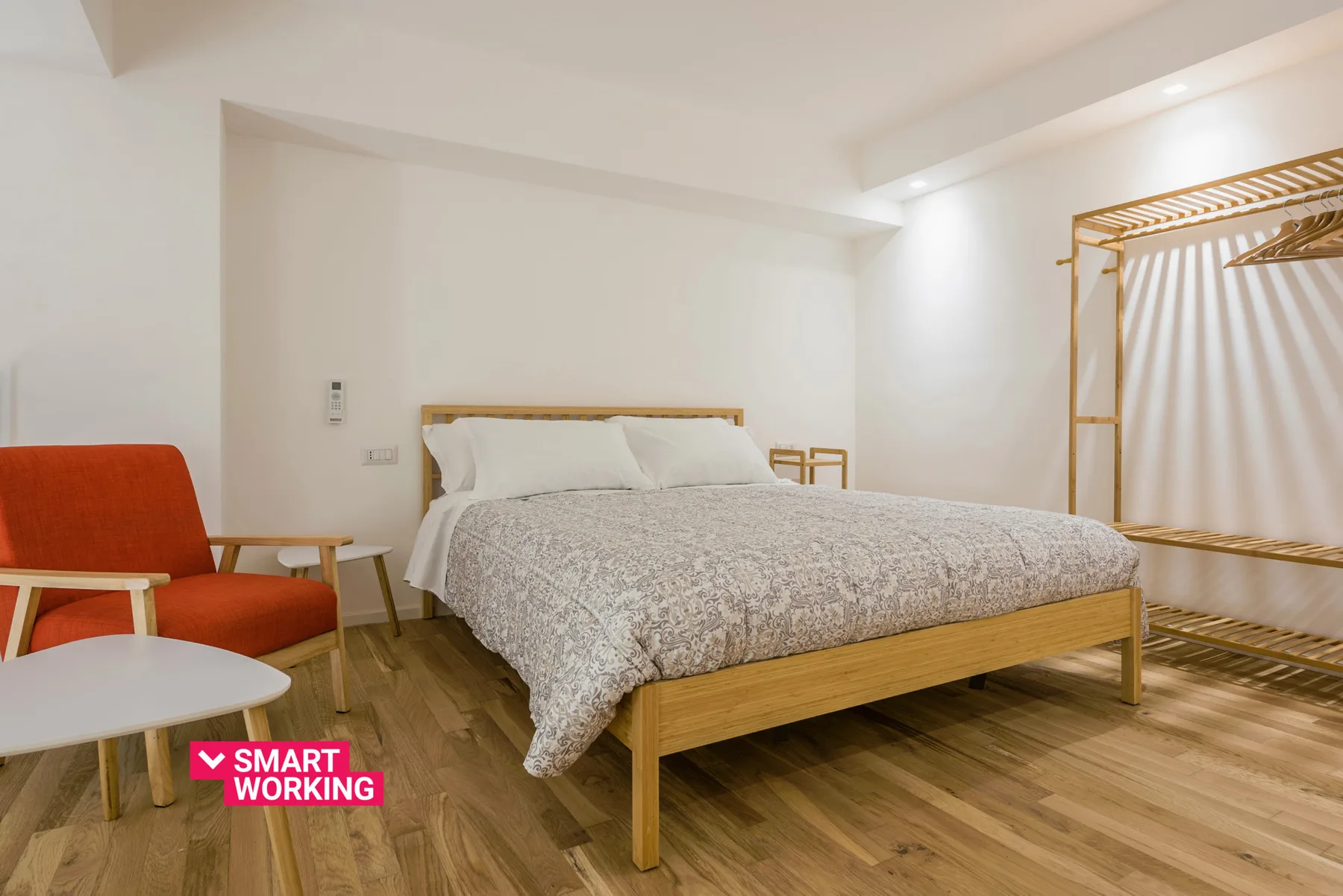 A bedroom with a bed, red seating, and a curtained dressing area.