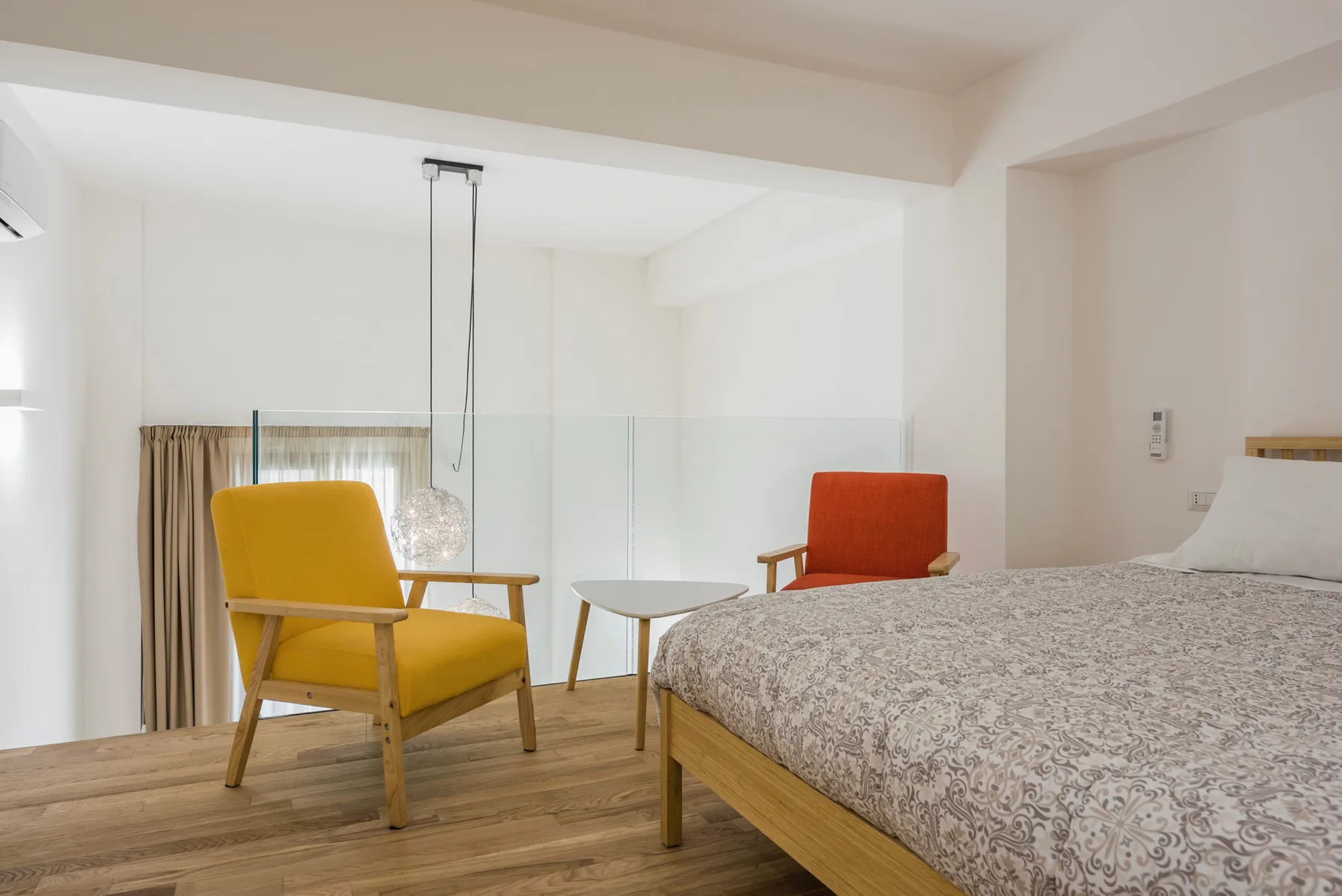 A bedroom with a patterned bed, two chairs, and a small table.