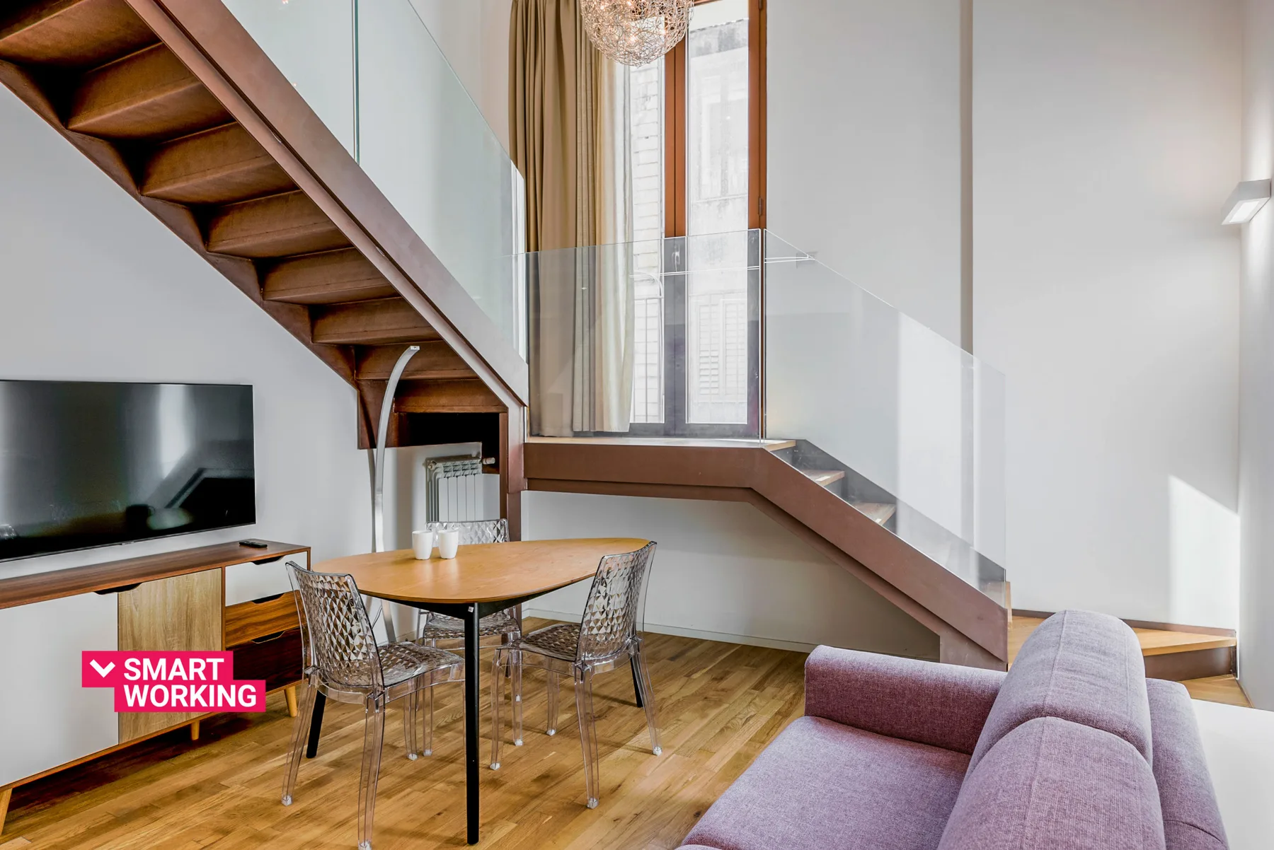 Una luminosa sala de estar con una mesa de comedor bajo una escalera.