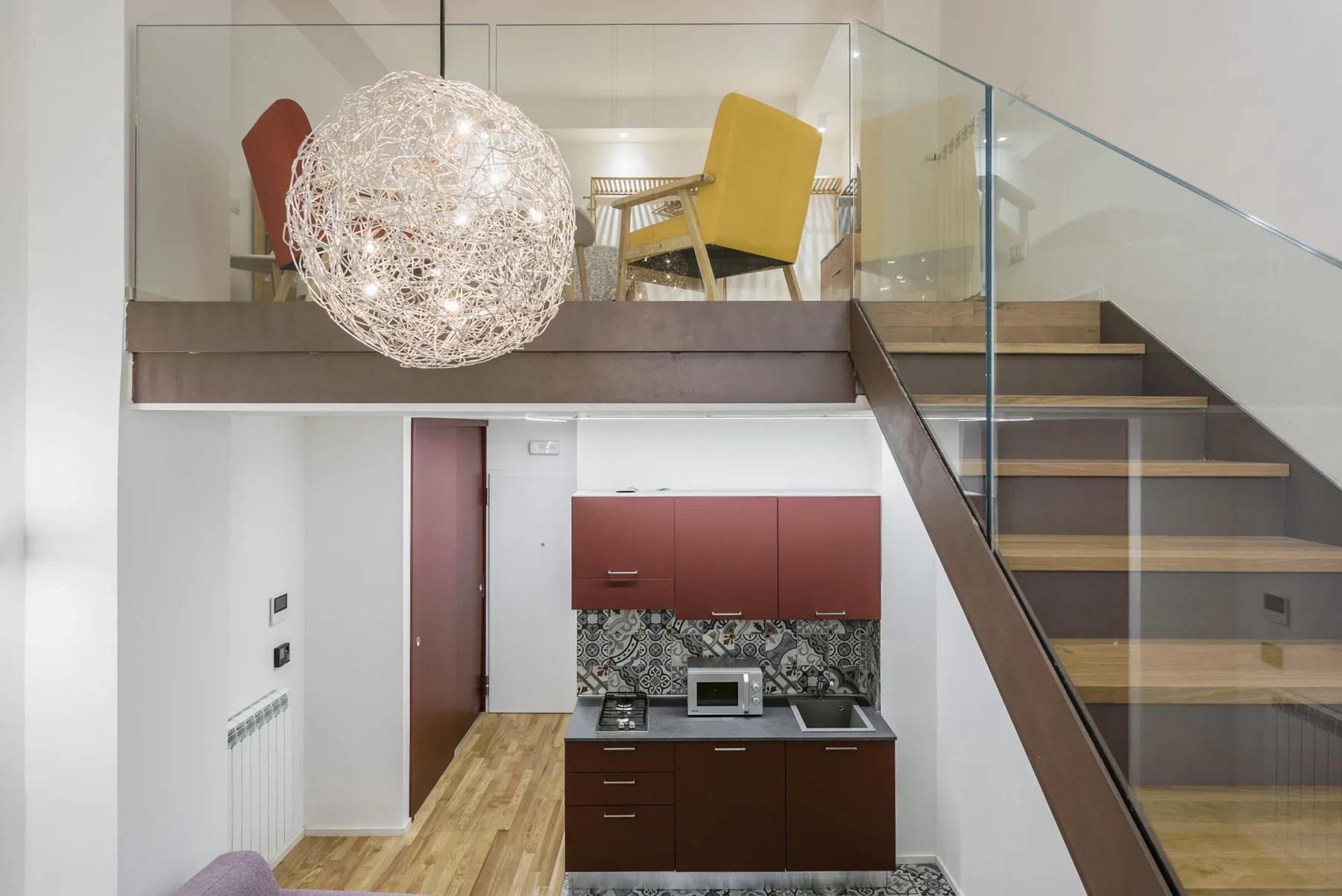 A split-level interior with a kitchen below and a staircase beside it.